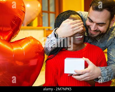 Porträt eines gemischtrassigen Paares mit einer weißen Schachtel, die ihre Augen am Valentinstag bedeckt Stockfoto