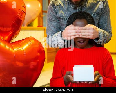 Porträt eines gemischtrassigen Paares mit einer weißen Schachtel, die ihre Augen am Valentinstag bedeckt Stockfoto