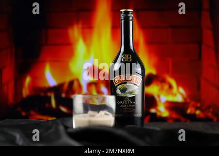 KIEW, UKRAINE - 4. MAI 2022 Baileys Original-Alkoholflasche auf Holztisch mit rotem Kamin im Hintergrund. Elite-Alkoholproduktion Stockfoto