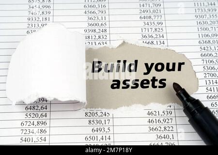 Geschäftskonzept. In der Mitte des Dokuments mit den Finanzberichten gibt es ein Loch mit der Inschrift: Erstellen Sie Ihre Assets Stockfoto