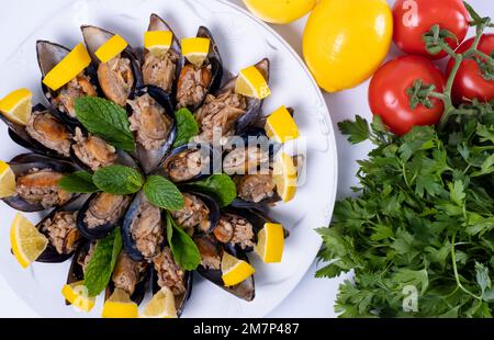 Türkisches Street Food gefüllte Muscheln und Zitrone auf Teller isolierter Holzhintergrund. Schwarze Schalentiere für Banner, Katalog oder Menü. Stockfoto