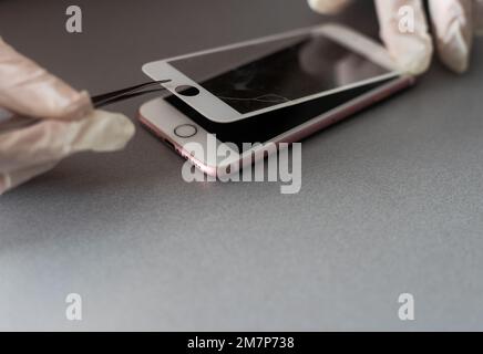 Smart Solution Technologiekonzept. Zugeschnittener Fotoersatz von Schutzfolie durch einen neuen. Man entfernt vorsichtig das alte Schutzglas aus dem Stockfoto