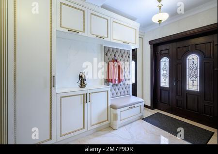 Elegante Eingangshalle mit Schrank, Aufbewahrungsbank und Hängestänge Stockfoto