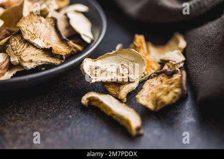 Geschnittene getrocknete Pilze auf dem schwarzen Tisch. Stockfoto