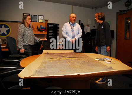 Susan Anderson (rechts) bietet einige Einblicke in die Flagge des Bundesstaates Indiana, die sie als Artefakt an das Hampton Roads Naval Museum spendet, an den Museumserzieher Zach Smyers (Mitte) und die stellvertretende Direktorin Toni Deetz-Rock (links). Die Flagge gehörte Andersons Vater, dem verstorbenen Captain Walter "Jack" Deal, USN, der während des Vietnamkriegs der befehlshabende Offizier des River Assault Squadron 15 war. Damals war es üblich, dass Bootskapitäne während des Vietnamkriegs die Staatsflagge ihres Heimatstaates auf ihren Flussangriffsbooten führten. Stockfoto