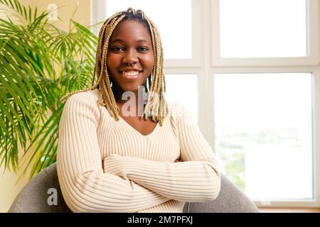 brasilianische Frau mit gelben Dreadlocks sitzt im Wohnzimmer Stockfoto