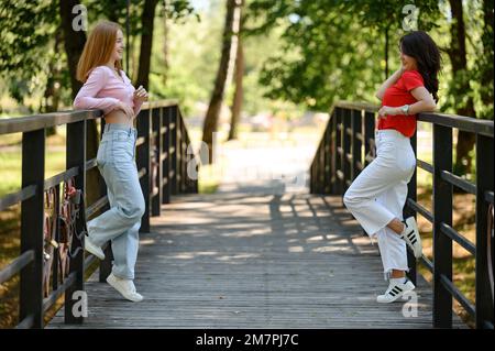 Ivano-Frankivsk, Ukraine 14. Juli 2022: Zwei Mädchen im Schulalter posieren auf einer Brücke für ihre gemeinsamen Porträts, Schulschießen. Stockfoto