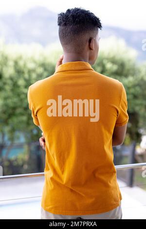 Bild der Rückansicht eines birassischen Mannes in orangefarbenem Kurzarm-Poloshirt mit Kopierraum Stockfoto