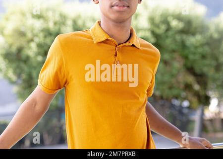 Bild eines birassischen Mannes im orangefarbenen Kurzarm-Polo-T-Shirt mit Kopierraum Stockfoto