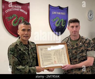 General Shingo Nashinoki, Befehlshaber der Amphibien-Schnelleinsatzbrigade, Japan Ground Self-Defense Force, stellte fünf US-Dollar vor Marineoffiziere der Marine Expeditionary Brigade 3. mit Dankestiteln an Bord von Camp Courtney, Okinawa, Japan, 11. Mai 2022 zu Ehren unserer engen Beziehung und harten Arbeit bei vergangenen Veranstaltungen wie den jährlichen Übungen Yama Sakura, die die Verteidigung Japans Proben. Oberst Michael 'Spud' Brennan, Operations Officer der MEB 3D, überreichte der ARDB CG auch ein kleines Geschenk, das unser gemeinsames Ziel und Engagement bei unserer Arbeit verdeutlicht Stockfoto