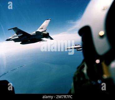 Eine linke Seitenansicht von zwei F-16A Kampfflugzeugen von Falcon, vom Innern eines anderen Falcon's Vordachs aus gesehen, während des Fluges. Die Flugzeuge sind von der 35. Taktischen Kampfstaffel, 8. Taktischen Kampfflug, die auf die Kunsan-Luftwaffe in Korea entsandt werden. Die Abbildung zeigt das führende Flugzeug mit einer Gepäckablage auf dem linken Flügel und zusätzlichen Kraftstofftanks. Land: Pazifik (POC) Stockfoto