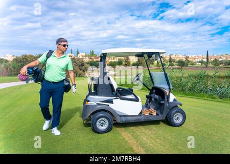 Ein Mann im Buggy mit der Tasche voller Schläger, der auf den Golfplatz schaut, Golfschläger, Fahrer, Eisen, Pitching Stockfoto