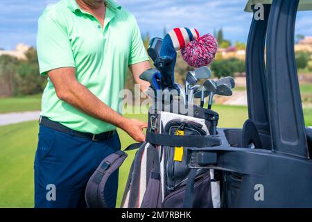 Ein Kaukasier im Buggy, mit einer Tüte Schläger, die Golf und Golfschläger spielen Stockfoto