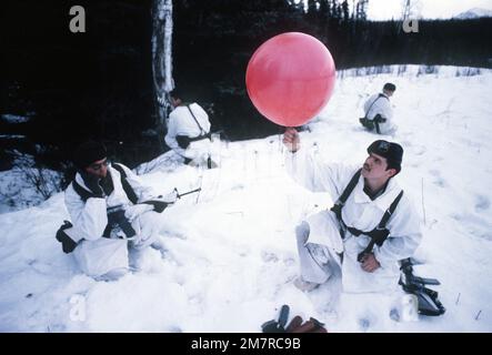 AIRMAN 1. Klasse Findley, Wetterspezialist, unter der Sicherheit der Green Beret Truppen, bereitet sich darauf vor, einen Heliumballon für eine Windmessung in einer Abwurfzone während der Übung Brim Frost '81 freizulassen. Der Flieger ist vom 5. Wetterdienst und die Green Beret Truppen sind von Co C, 2. Mrd. $, 7. Spezialeinheiten. Basis: Clear Creek Bundesstaat: Alaska (AK) Land: Vereinigte Staaten von Amerika (USA) Stockfoto