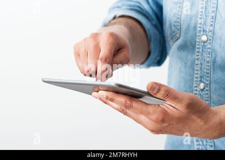 Zugeschnittene Aufnahme eines unbekannten Geschäftsmanns, der allein in seinem Heimbüro steht und auf seinem digitalen Tablet surft Stockfoto