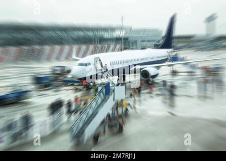 Fluggäste und Arbeiter eines nicht identifizierten Flugzeugs. Verschwommenes Zoombild. Stockfoto