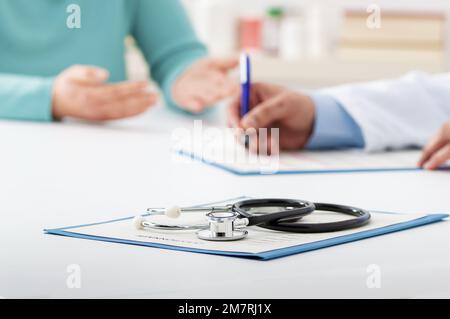 Freigestellte Aufnahme einer Patientin, die mit einem männlichen Arzt in seiner Praxis spricht Stockfoto