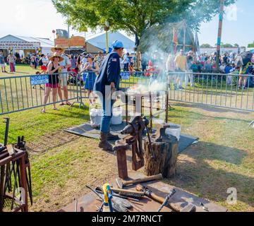 NEW ORLEANS, LA, USA - 1. MAI 2022: Der Assistent des Schmieds stottert das Feuer im Blacksmith Demo Annex beim New Orleans Jazz and Heritage Festival Stockfoto