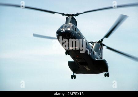 Linke Unteransicht eines CH-46D Sea Knight Hubschraubers vom Helicopter Combat Support Squadron 3 (HC-3), Ablösung 103. Der Hubschrauber ist dem Munitionsschiff der Kilauea-Klasse USS KISKA (AE 35) zugewiesen. Land: Unbekannt Stockfoto