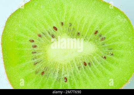 Frische Kiwis in Flüssigkeit mit Blasen. Nahaufnahme eines Kiwis in Sodawasser. Blasen auf Kiwis. Scheibe Kiwis in Kohlensäure Stockfoto