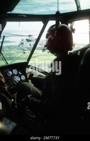 Eine Luftaufnahme eines SH-3 Sea King Hubschraubers aus dem Cockpit-Fenster eines anderen SH-3. Beide Hubschrauber sind der Flotte Composite Squadron 5 (VC-5) zugewiesen. Land: Philippinen (PHL) Stockfoto