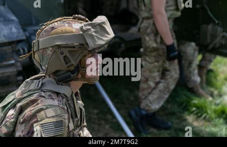 EIN US-AMERIKANISCHER Der Soldat beobachtet, wie ukrainische Artilleristen auf dem Trainingsgelände Grafenwoehr, Deutschland, den selbstfahrenden Haubitzer M109 am 12. Mai 2022 abfeuern. Soldaten aus den USA und Norwegen trainierten Artilleristen der Ukraine auf den Haubitzen als Teil von Sicherheitspaketen aus ihren jeweiligen Ländern. Stockfoto