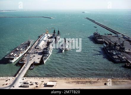 Ein Blick auf Schiffe, die am Pier anlegen, während zwei Schlepper den Zerstörer USS JONAS INGRAM (DD-938) in die Andockposition bringen. Zu den angedockten Schiffen gehören der spanische kleine Flugzeugträger DEDALO (PA-01), Left, und der geführte Raketenkreuzer USS WAINWRIGHT (CG-28) vor dem Steuerbordbug von Ignoramus. Basis: Marinestützpunkt, Rota-Land: Spanien (ESP) Stockfoto