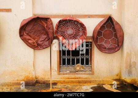 Fez, Marokko - in der Chouara Tannery in Fez el Bali hängen drei runde, braune, behandelte, ungefüllte Lederottomanen an der Wand zum Trocknen. Zum Verkauf oder zur Ausfuhr bestimmte Waren. Stockfoto