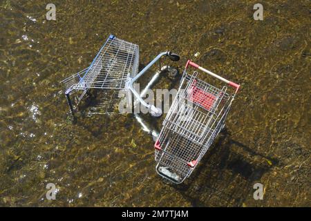 Gestürzte Einkaufswagen im flachen Wasser Stockfoto