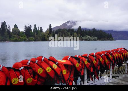 Eine Reihe roter Rettungswesten über einem Zaun am Ufer des Lake Wakatipu Stockfoto