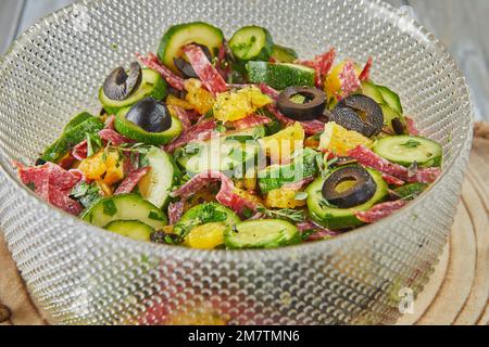 Salat mit Zucchini, Orangen und Salami der französischen Gourmetküche auf Holzhintergrund. Stockfoto