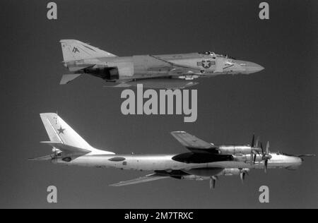 Eine Luft-Luft-Seitenansicht von rechts eines US-amerikanischen Navy F-4 Phantom II Flugzeug, Top, von Fighter Squadron 74 (VF-74) und ein sowjetisches TU-95 Tupolev Bear Flugzeug etwa 42 Meilen vor der Küste von Virginia. Die F-4 begleitet die in Kuba ansässige TU-95, die gerade in die US-Luftwaffenzone eingedrungen ist, um Seeversuche des neuen nuklearbetriebenen Flugzeugträgers CARL VINSON (CVN-70) aus der Vogelperspektive zu betrachten. Land: Atlantik (AOC) Stockfoto