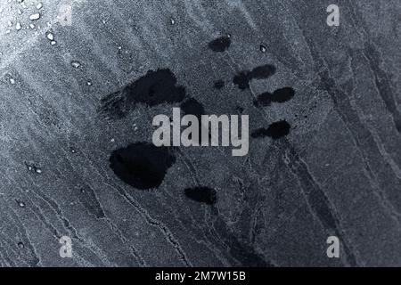 Nasser Handdruck auf rauer, gefrorener schwarzer Metalloberfläche Stockfoto