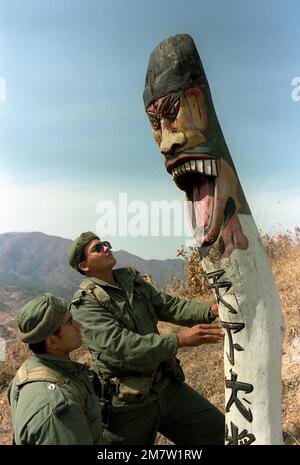 Zwei Mitglieder der Combat Support Co., 1. Mrd. $, 35. Inf., 25. Inf. Div., sehen Sie sich eine große hölzerne religiöse Statue an, während Sie auf Patrouille im südkoreanischen Spezialeinsatzgebiet sind. Die Soldaten nehmen an der gemeinsamen südkoreanischen/US-Trainingsübung Team Spirit '82 Teil. Betreff Operation/Serie: TEAMGEIST '82 Basis: Geon Cha Land: Republik Korea (KOR) Stockfoto