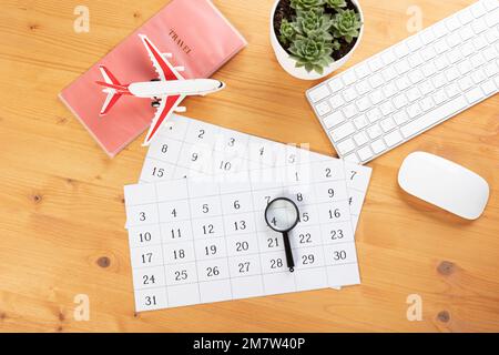 Kalender und Erinnerungen für Geschäftsreisen, Reisen und Urlaub. Gleiter auf dem Schreibtisch mit Flugzeug und Lupe, Stift und Tastatur. Markierung wichtig Stockfoto