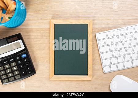 Modell einer Schultafel auf dem Schreibtisch. Zusammensetzung eines Schülerschreibtisches mit Schreibwaren, Spielzeug, Imbiss. Leere Tafel für Werbetext Stockfoto