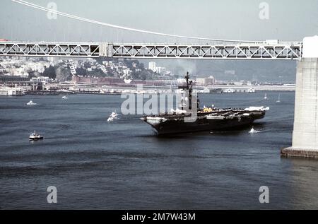 Ein Hafenbogenblick auf den Flugzeugträger USS CORAL SEA (CV-43) unter der San Francisco-Oakland Bay Bridge. Das Schiff ist auf dem Weg zur Naval Air Station, Alameda, nach einer Western Pacific (WESTPAC) Kreuzfahrt. Basis: San Francisco Bay Bundesstaat: Kalifornien (CA) Land: Vereinigte Staaten von Amerika (USA) Stockfoto
