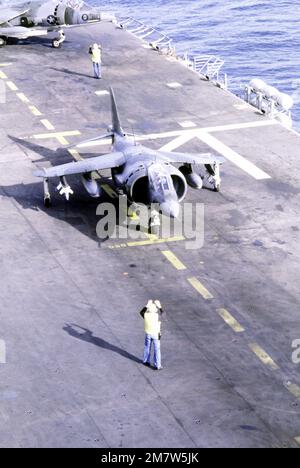 Ein Besatzungsmitglied des Cockpits signalisiert dem Piloten eines AV-8A-Harrier-Flugzeugs, das sich auf den Start vom Cockpit an Bord des Amphibienschiffs USS NASSAU (LHA-4) vorbereitet. Land: Atlantik (AOC) Stockfoto