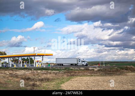 Industrieller Standard weißer großer Lkw mit Trockenwagen Auflieger steht nach dem Befüllen der Tanks mit Diesel wa auf dem Parkplatz der Tankstelle Stockfoto