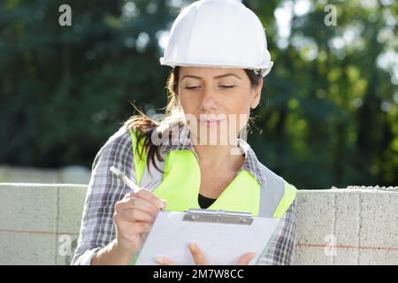 Frau Baufachingenieurin, die auf das Klemmbrett schreibt Stockfoto