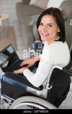Lächelnde junge, wunderschöne behinderte Frau im Rollstuhl Stockfoto