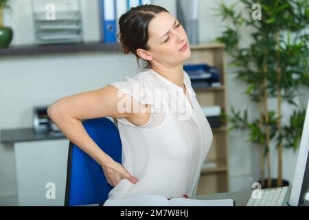 Frau mit Rückenschmerzen im Büro Stockfoto