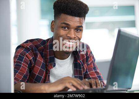 Junger Mann, der auf dem Laptop tippt Stockfoto