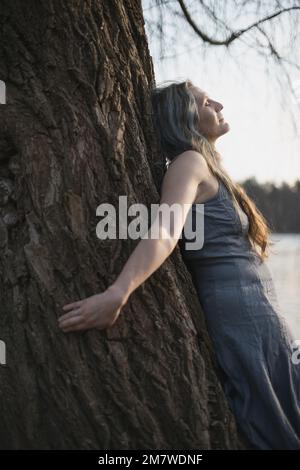 Nahaufnahme einer Frau, die sich spirituell mit einem Weidenbaum-Porträtbild verbindet Stockfoto