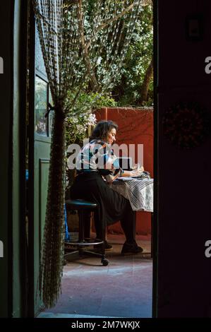 Vertikales Bild einer erwachsenen Kaukasierin, die auf der Terrasse arbeitet, durch die offene Tür vom Inneren des Hauses gesehen, Kopierraum. Stockfoto
