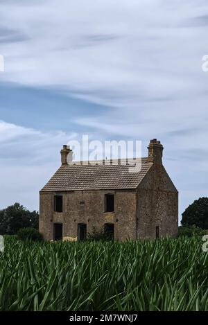 Verlassenes leeres Haus, allein auf den Feldern, gruseliger mysteriöser Bucheinband-Stil. Stockfoto