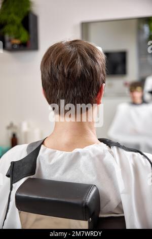 Ein hübscher junger Mann sieht sein Spiegelbild im Spiegel Stockfoto
