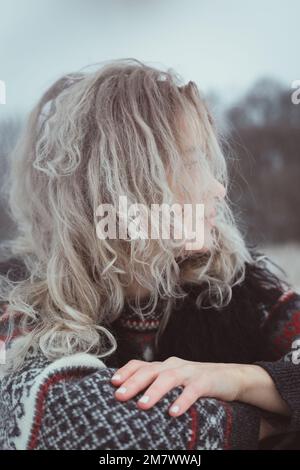 Nahaufnahme einer Frau mit lockigem Haar in einem warmen Pullover im Außenporträt Stockfoto