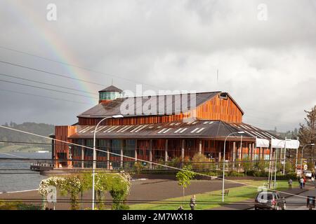 Frutillar, Chile-17. oktober 2014: Regenbogen über El Teatro del Lago. Die Leute gehen nach dem Regen vor dem Theater des Sees. Stockfoto