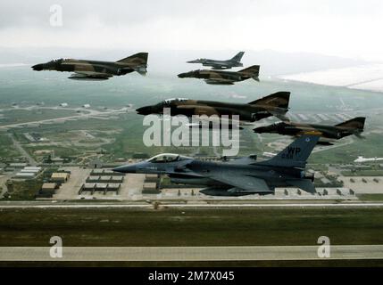 Eine linke Seitenansicht von vier F-4D Phantom II-Flugzeugen im Vordergrund, die beim letzten Verlassen der Basis von zwei F-16-Kampfflugzeugen im Hintergrund begleitet werden. Basis: Land des Luftwaffenstützpunkts Kunsan: Republik Korea (KOR) Stockfoto